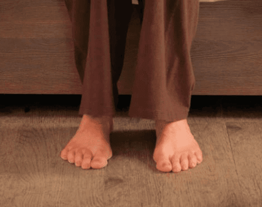 A person's feet on a wooden bed.