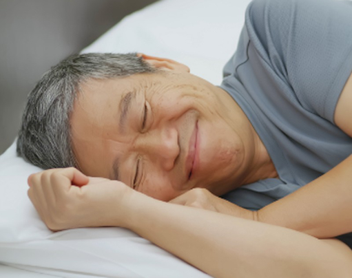 An asian man is sleeping on a bed.