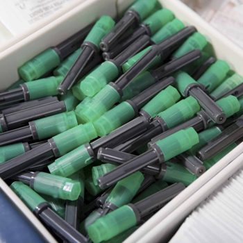 a box filled with lots of green and black markers.