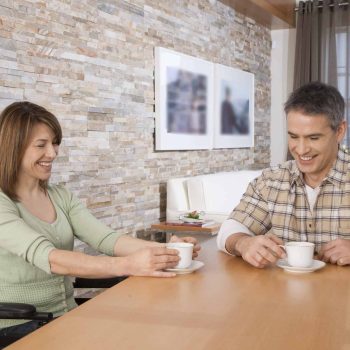 a man and a woman sitting at a table with cups of coffee.